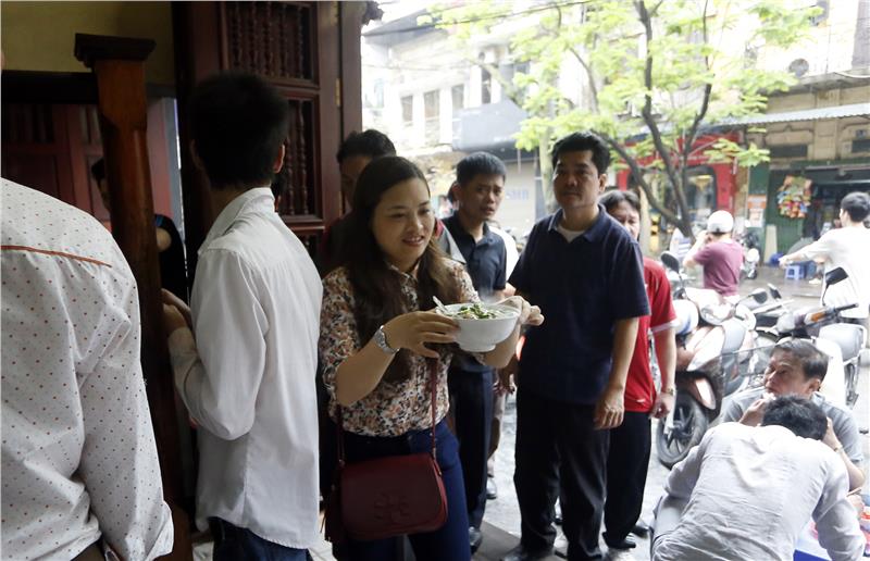 A customer take her own bowl of Pho Bat Dan